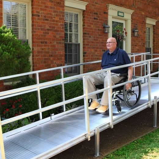 man on wheelchair goes down an exterior ramp