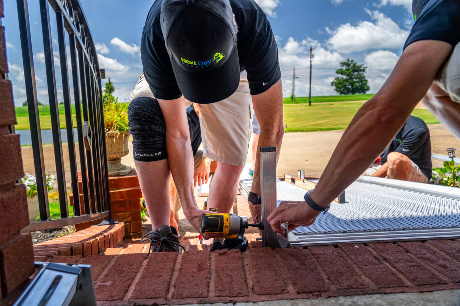 A crew in uniform installing a wheelchair ramp outside of a homeowner's front door