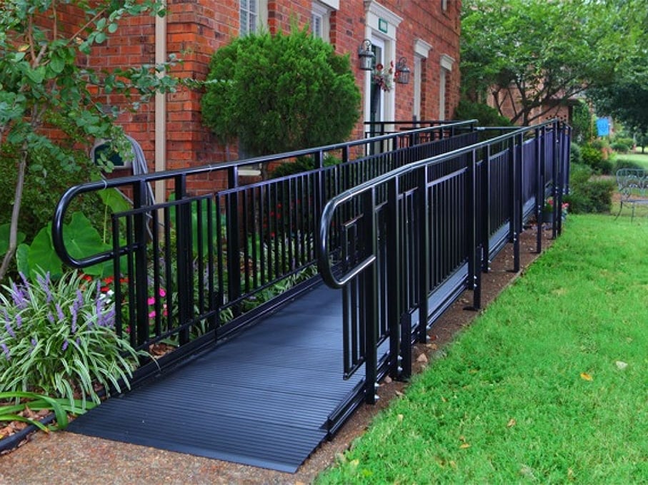 A black ramp with a 90 degree angle runs alongside of a brick building