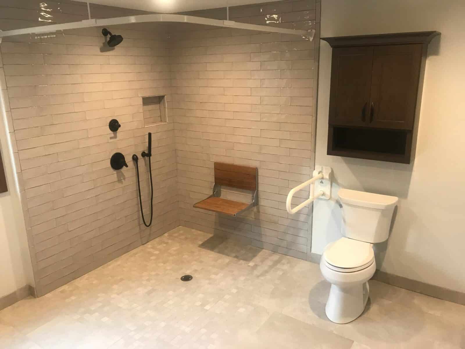 open shower with no walls next to a toilet in a tiled bathroom
