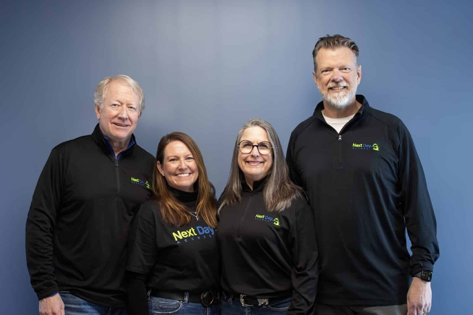 Diverse team of eight people, all dressed in casual business attire, standing together for a photo outside.