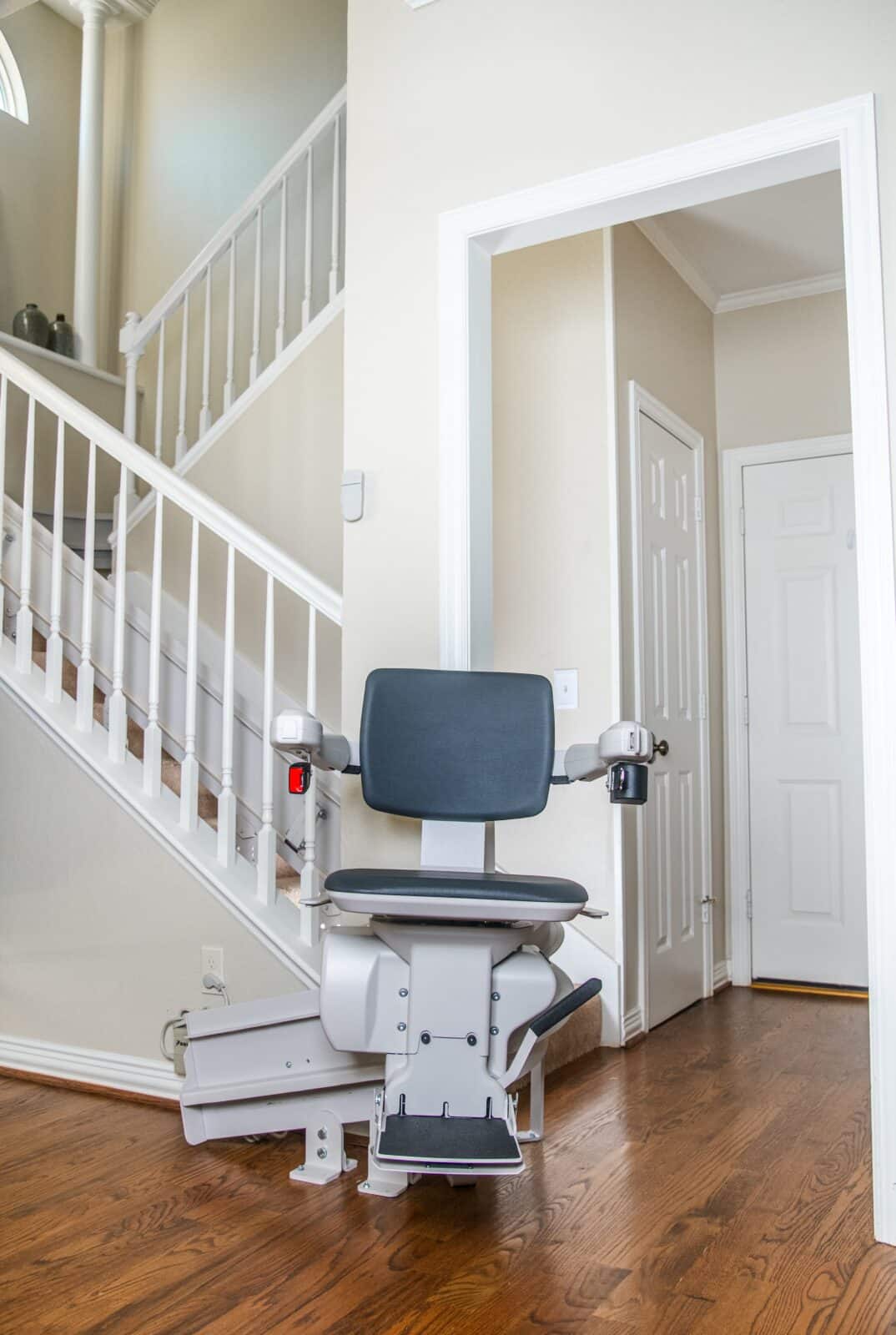 Woman in a blue sweater smiles and sits at the bottom of the stairs on a chair lift