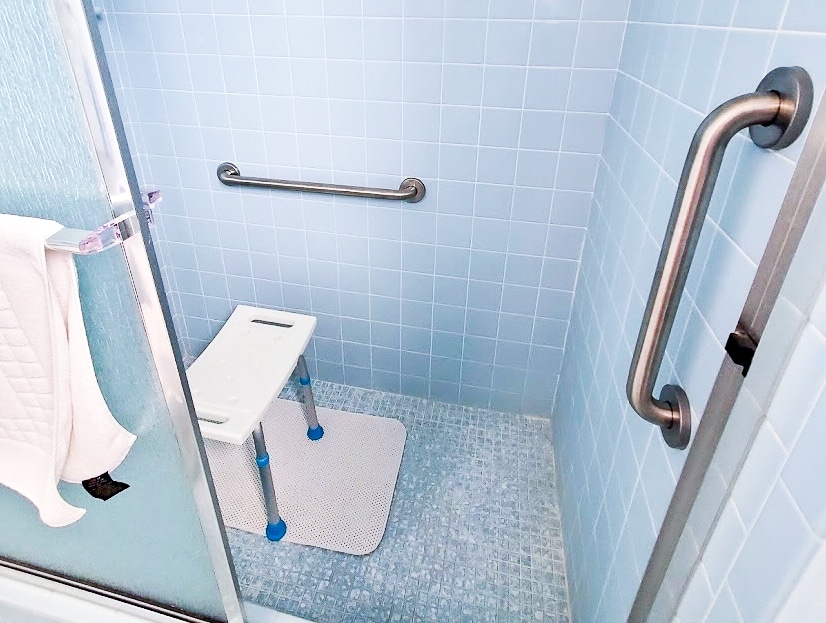 a bright blue shower with grab bars and a shower chair