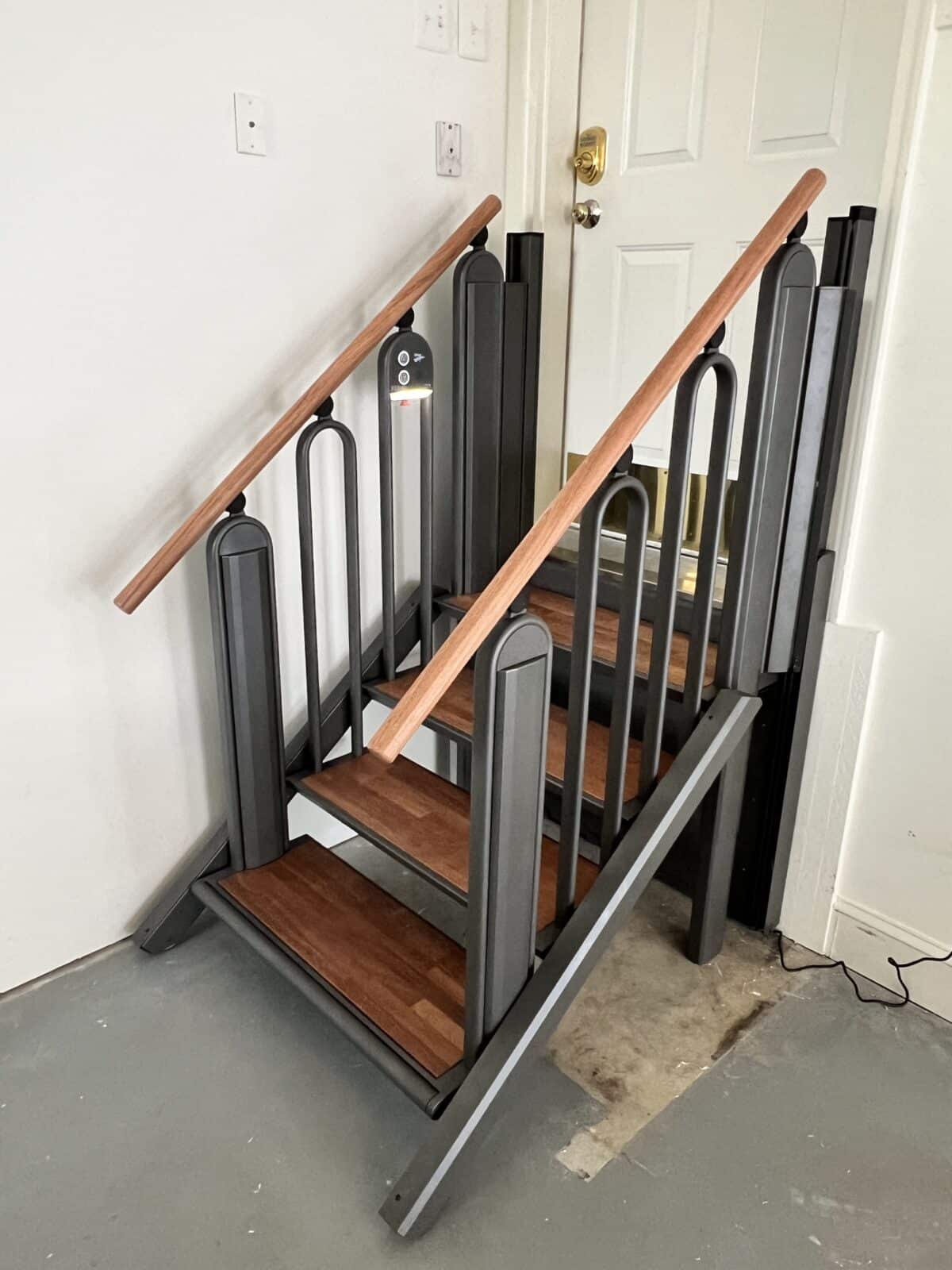 a long winding metal ramp that zig zags up a steep hill next to a cement staircase