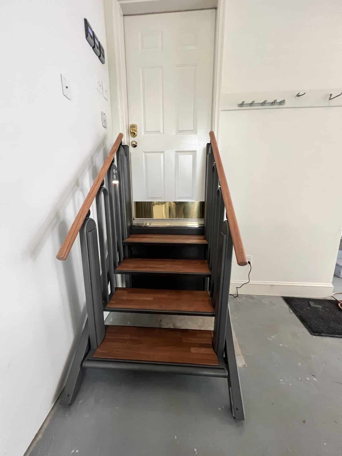a black porch lift installed between a wall and a brown stone staircase. 