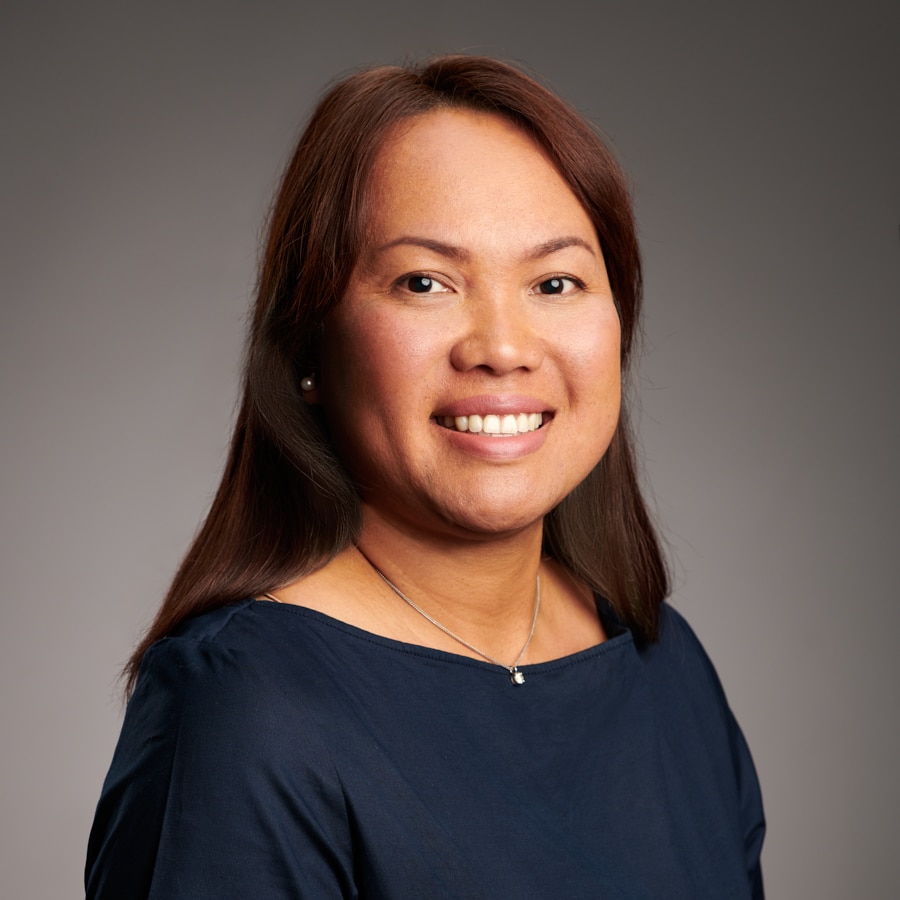 Headshot of Phairat Rice, a woman with long brown hair, smiling in a dark blue top.