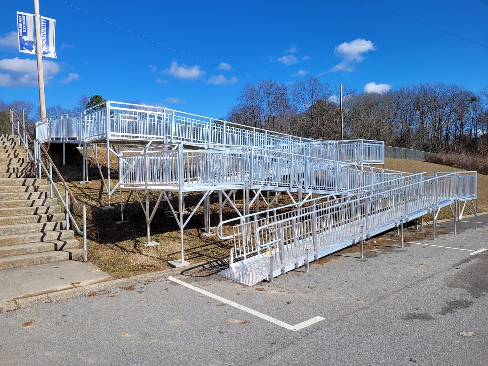 a long winding metal ramp that zig zags up a steep hill next to a cement staircase