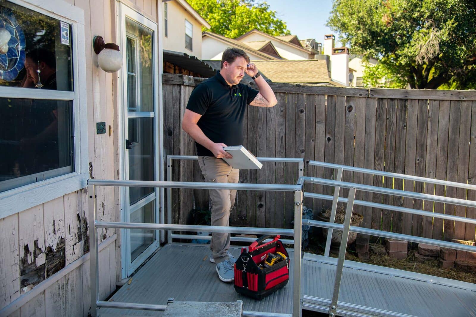 outdoor ramp is installed by a uniformed worker with a red tool bag at his feet
