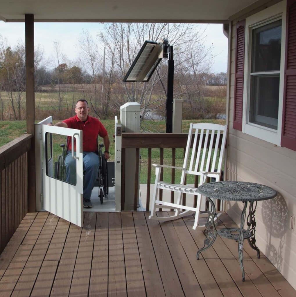 Man opens the door of his porch lift at the top of his deck