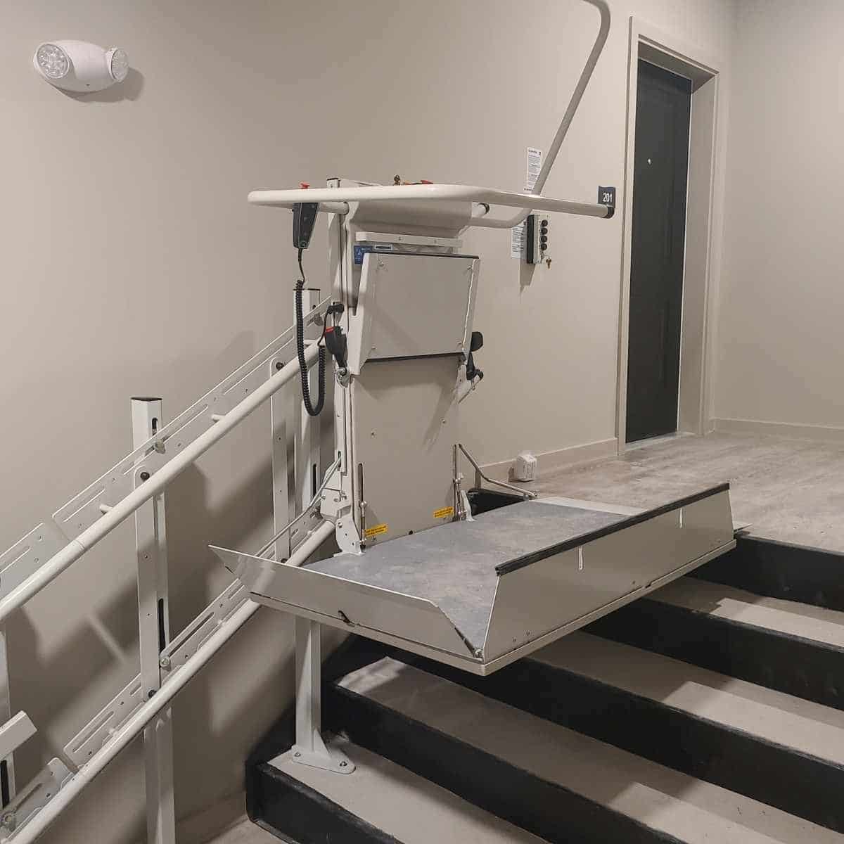a metal platform lift with no sides sits at the top of a commercial building stairwell