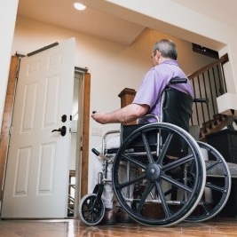 man in a wheelchair waits for his home door to be opened by an automatic opener installed on top