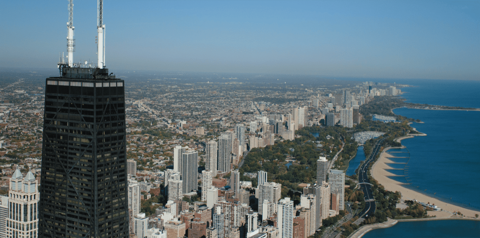 Aerial view of the Chicago skyline and lakefront, featuring the John Hancock Center in the foreground.