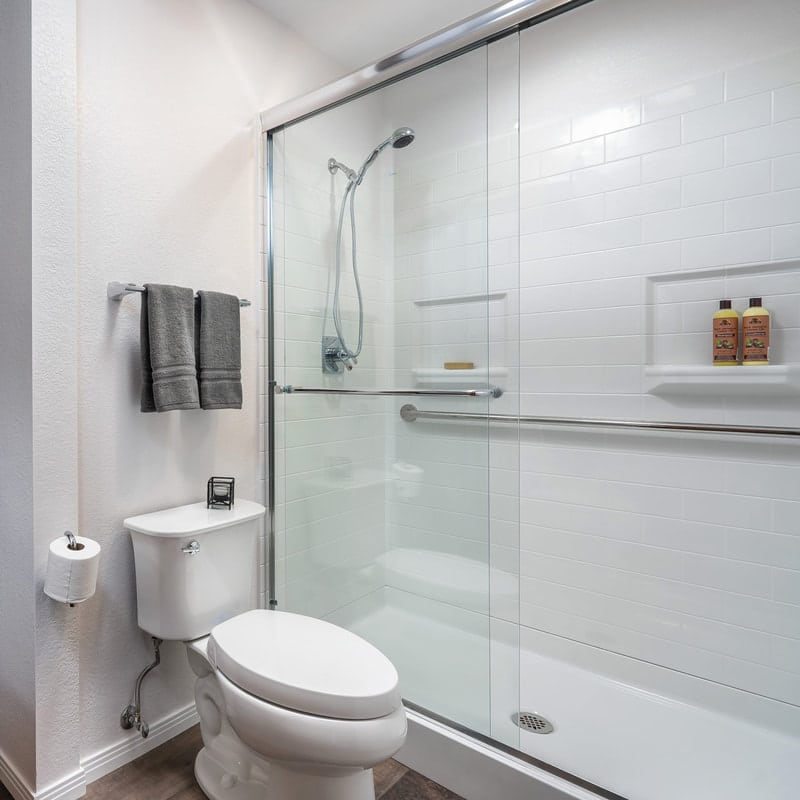 a clean, white bathroom with a number of grab bars installed