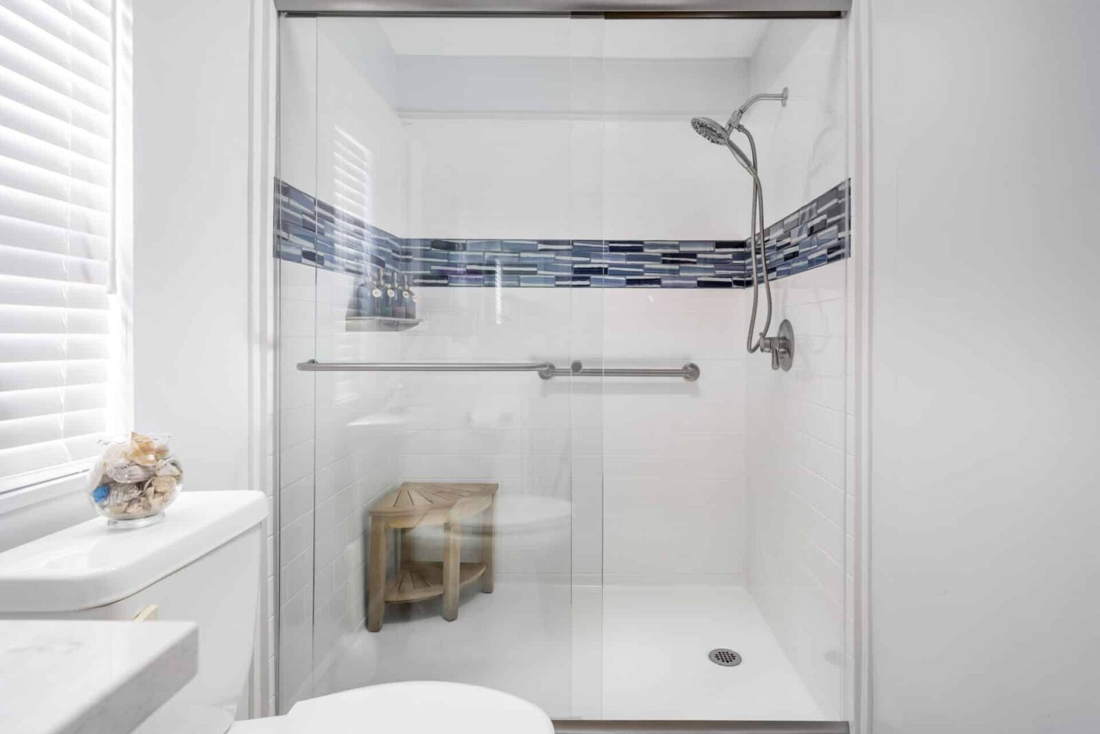 a white and blue titled shower with hand rails