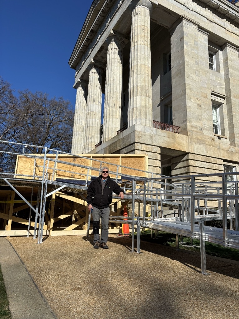 Man by an ADA-compliant modular aluminum wheelchair ramp during installation at the NC State Capitol.