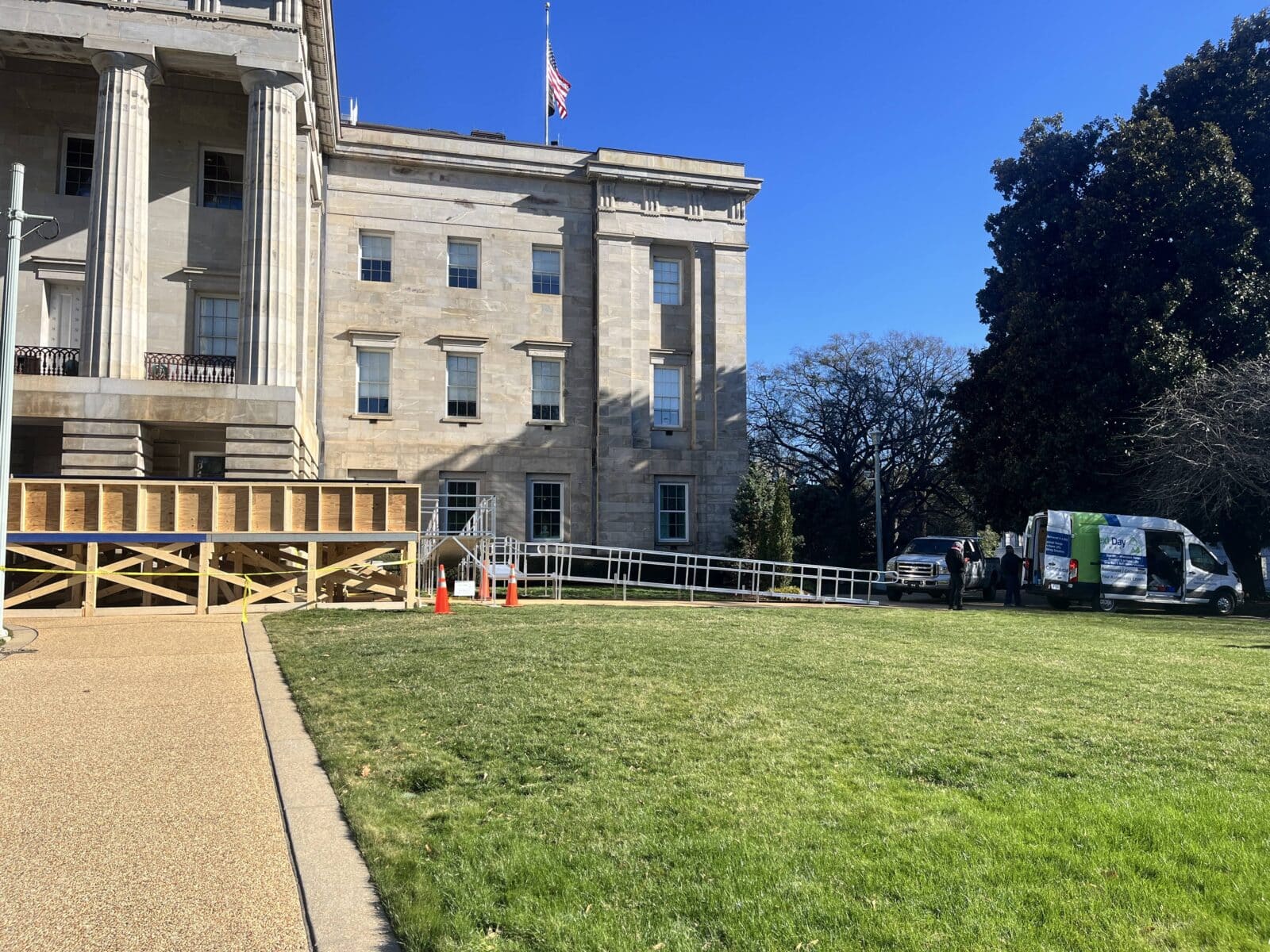 Workers installing an ADA-compliant commercial wheelchair ramp outside the NC State Capitol building.