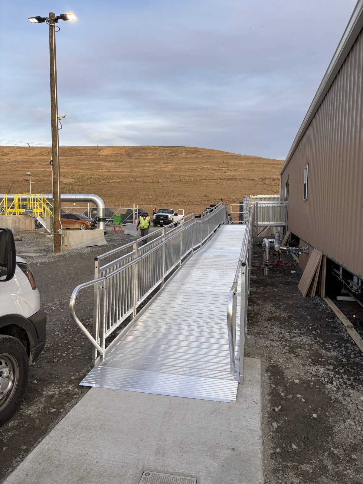 Long modular aluminum wheelchair ramp leading to the entrance of a commercial construction office.