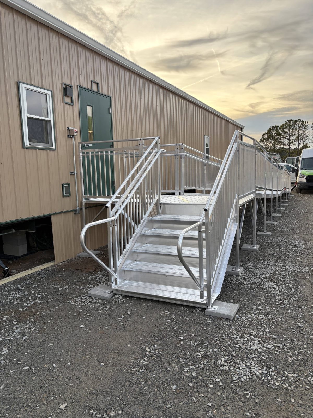 Aluminum stairs and an ADA-compliant commercial wheelchair ramp attached to a construction office.