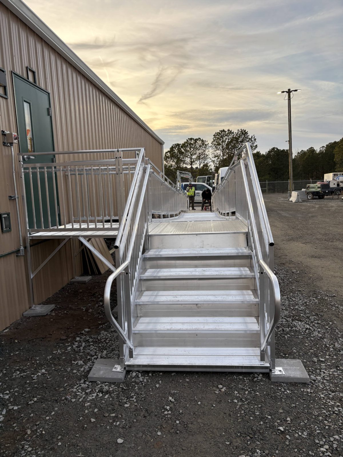 Front view of aluminum stairs connecting to a modular aluminum wheelchair ramp landing at an office.