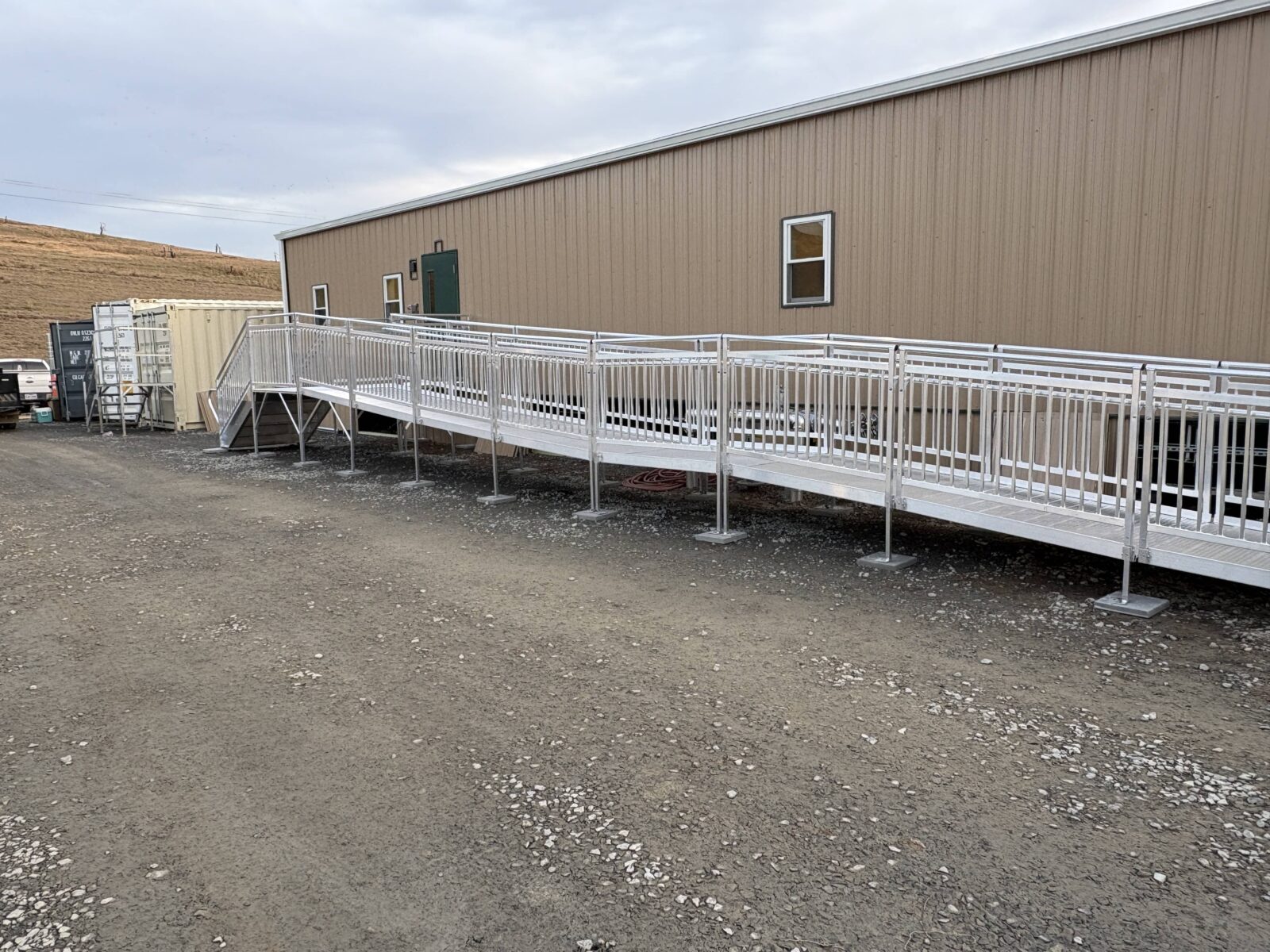 Side view of an ADA-compliant commercial wheelchair ramp spanning the length of a construction office.