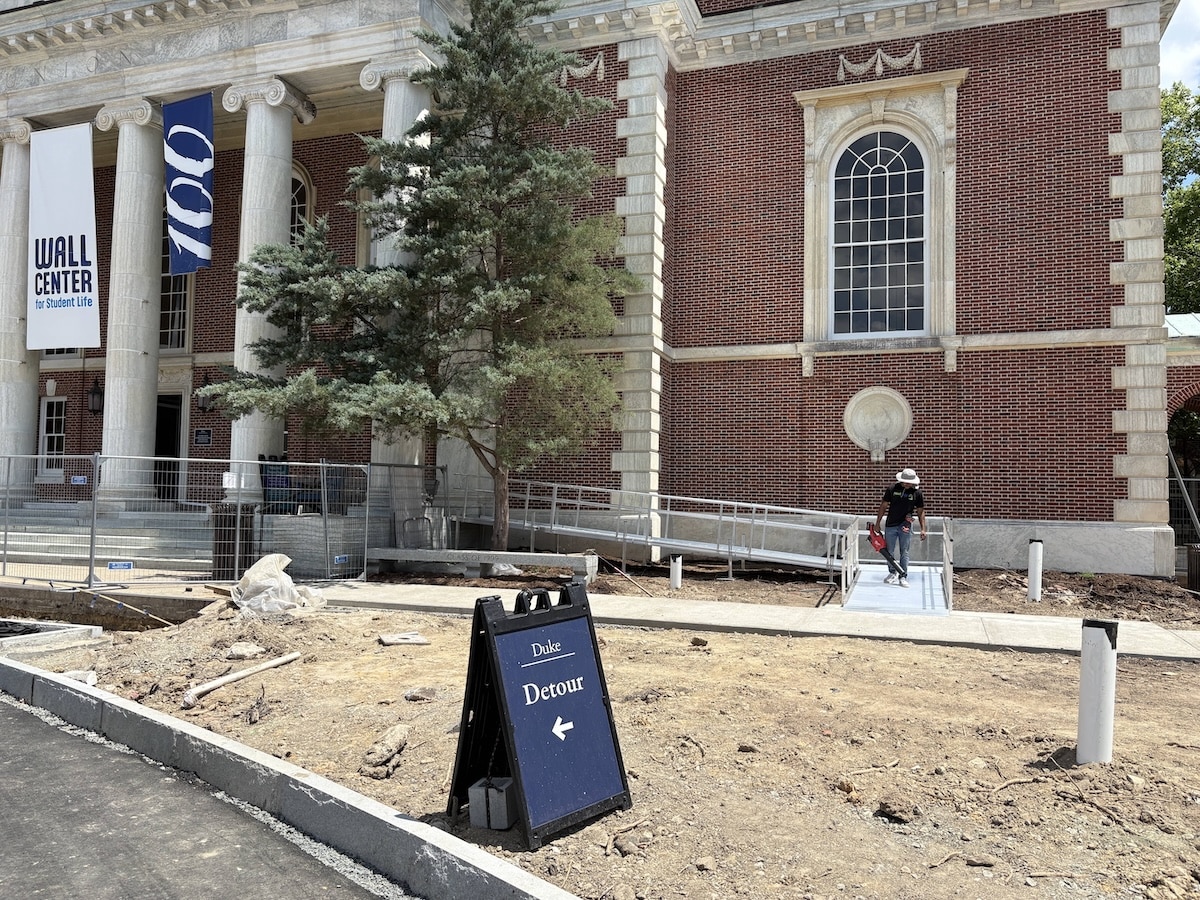 Worker finishing an ADA-compliant aluminum wheelchair ramp installation at Duke University.
