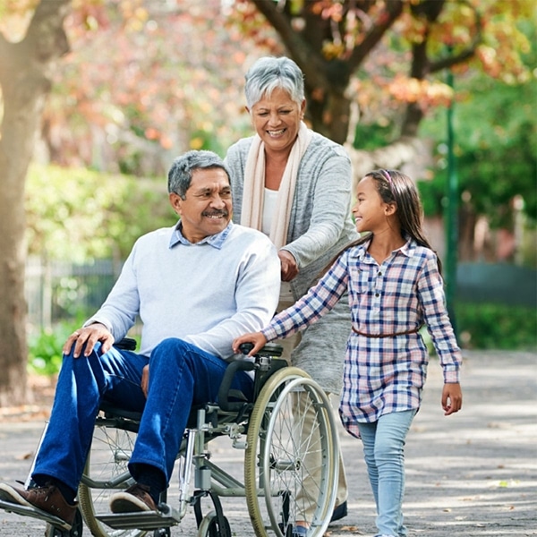 a family walks alongside a man in a wheelchair