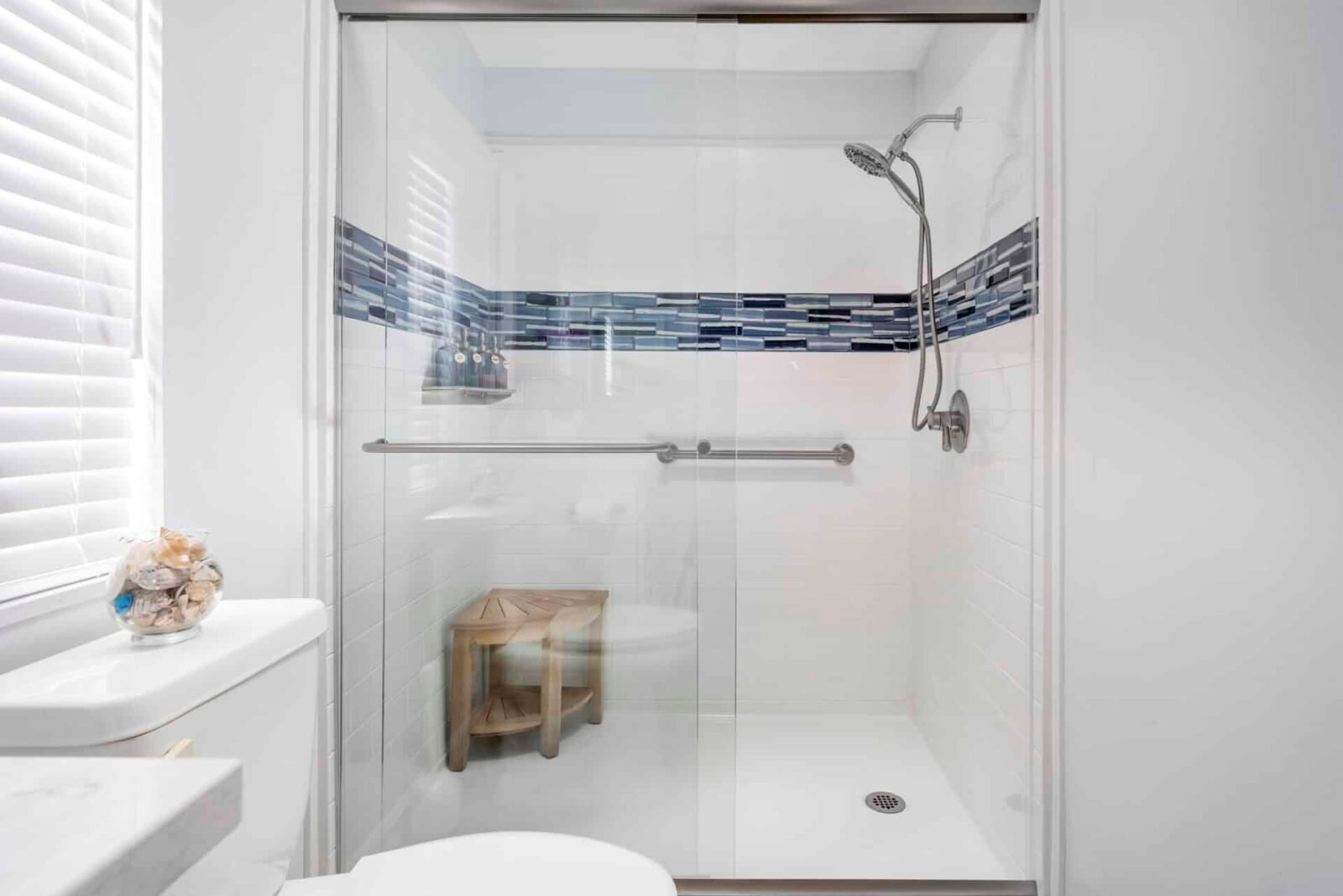 a white and blue titled shower with hand rails