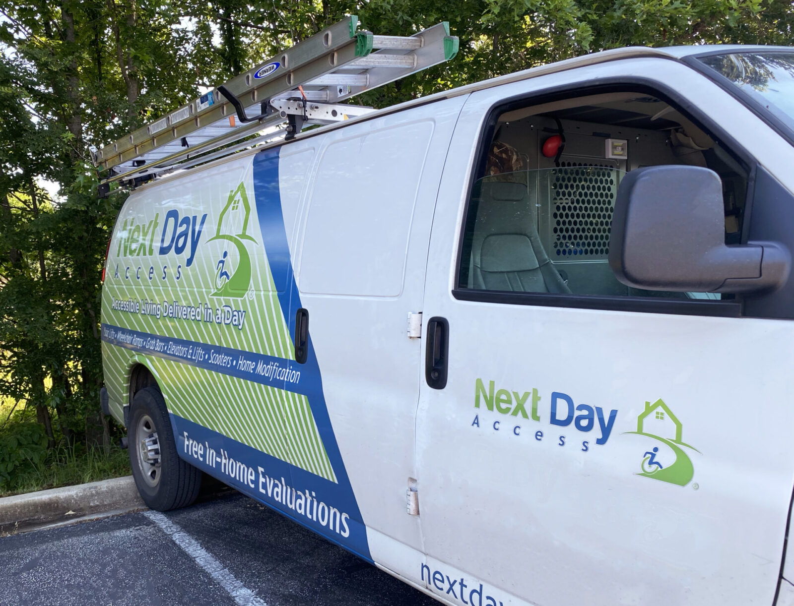 White service van with a ladder on the roof and "Next Day Access" logo and text on the side panel.