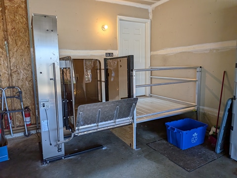 Vertical platform lift installed in a garage providing wheelchair access to an elevated home entrance