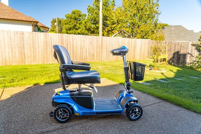 a blue motorized scooter sits unattended outside in a driveway
