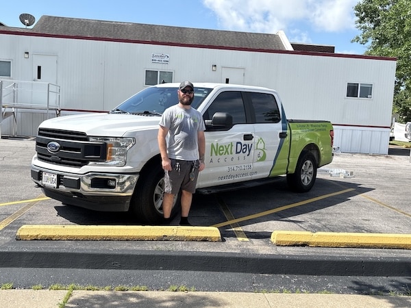 Devin Carter, Technician, standing with a Next Day Access truck