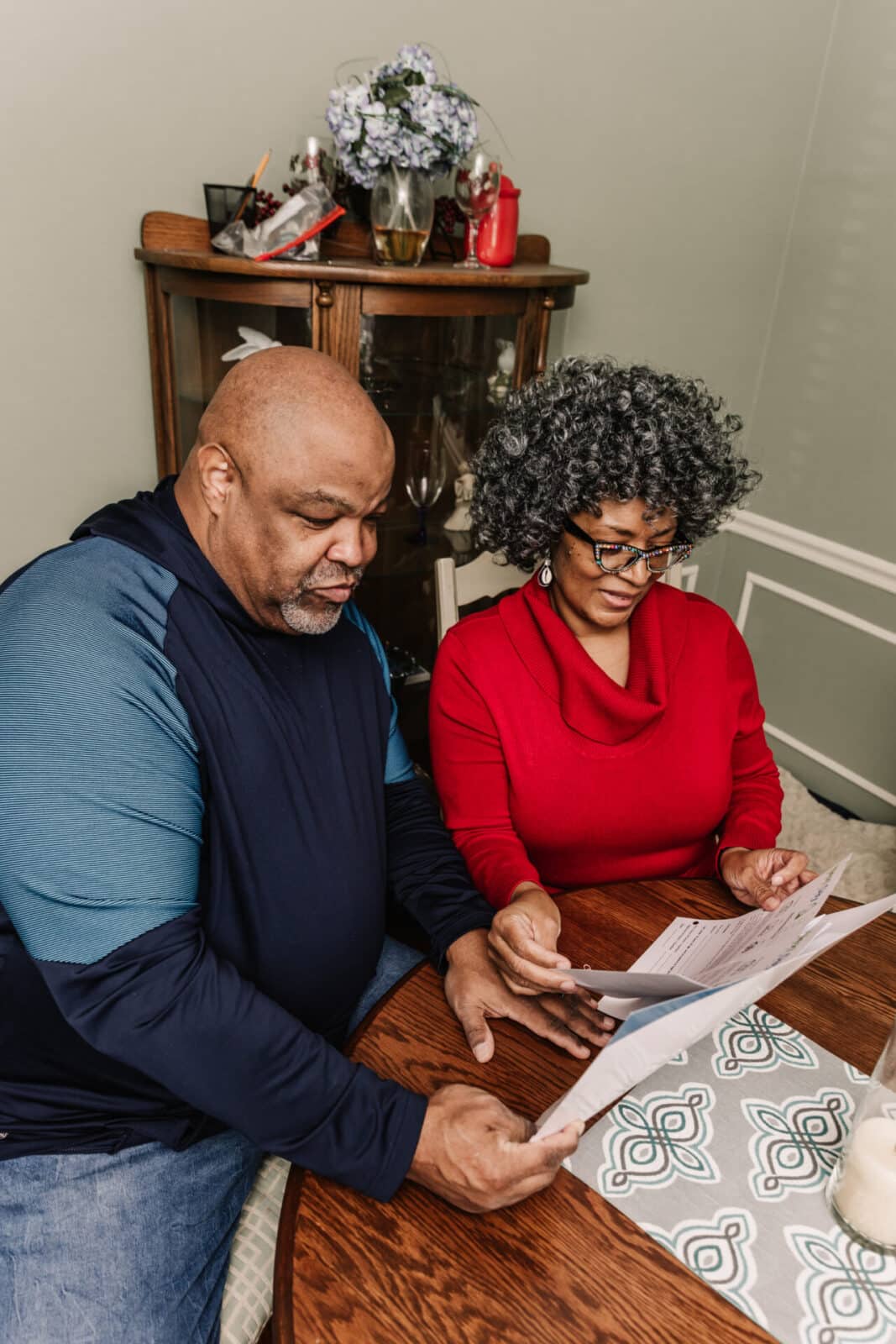 A man in uniform sits on the couch with a homeowner and discusses a project