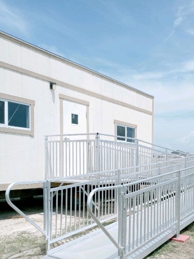 Outside of a mobile home trailer with a temporary ramp installed that leads to the door