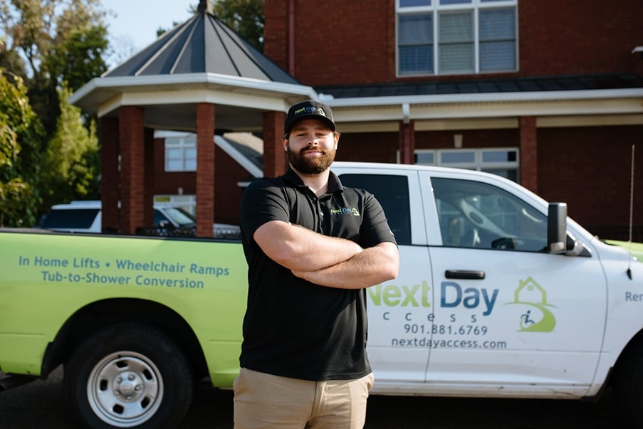 Next Day Access employee poses with his arms crossed in front of a company pick up truck