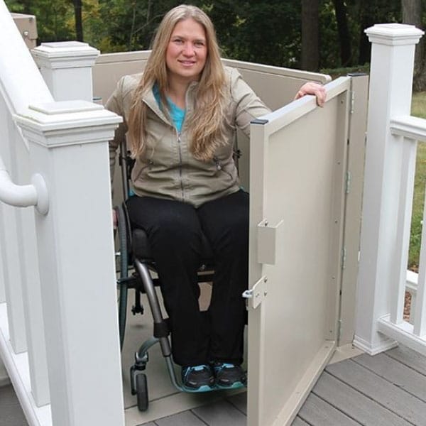 woman opens the door to her porch lift after being raised up to her deck