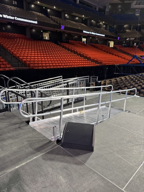 ramp in front of a black stage inside an arena full of red chairs