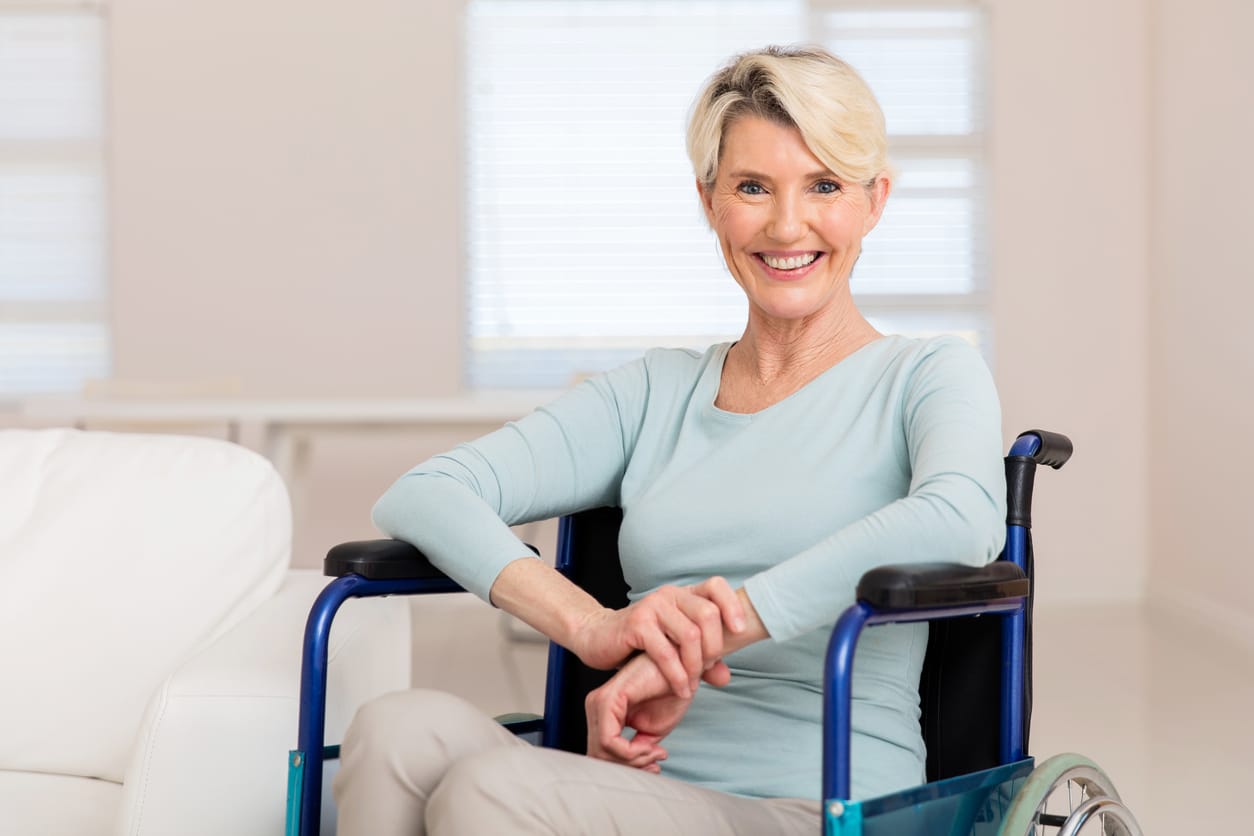 happy mid age woman sitting on wheelchair and recovering from sickness