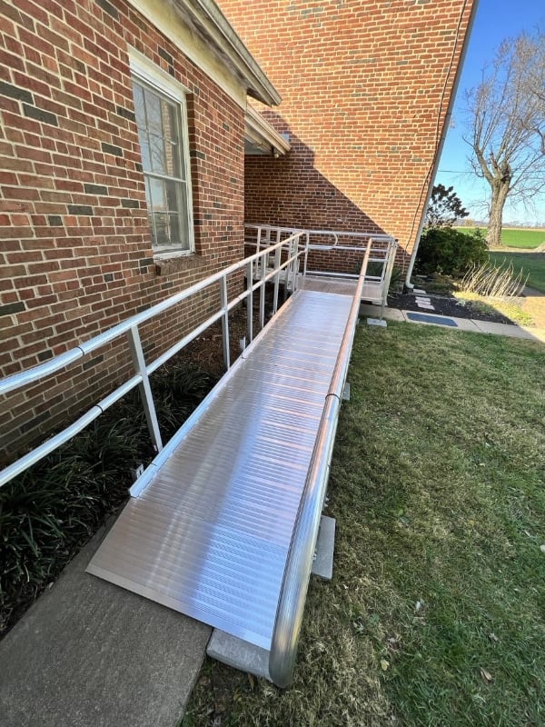 a Man in a uniform and baseball cap installs a handrail onto the bathroom wall