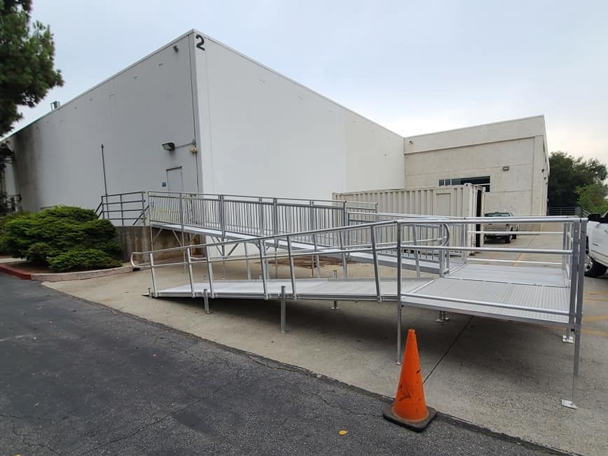 traffic cones sit on the ground in front of a warehouse with a wheelchair ramp installed