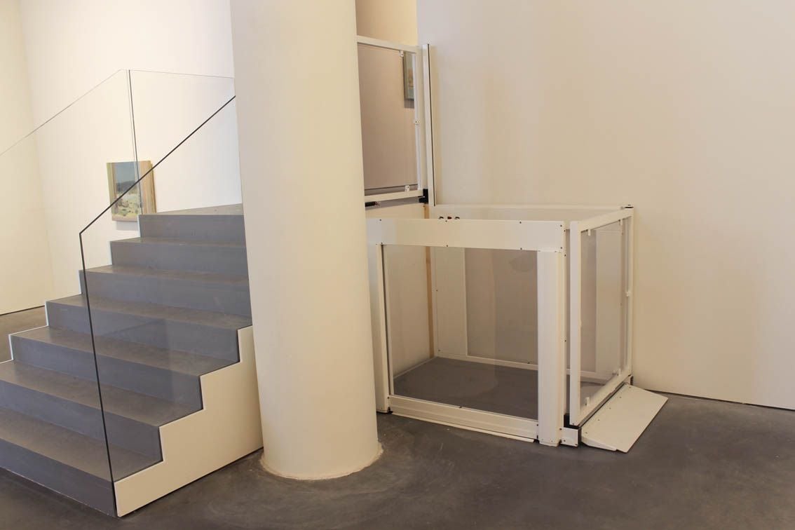 a commercial lift installed inside of a building next to a concrete pillar and staircase