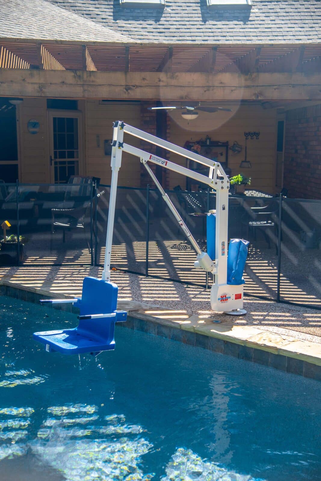 White pool lift with blue seat and "Revolution XL" text at pool edge.