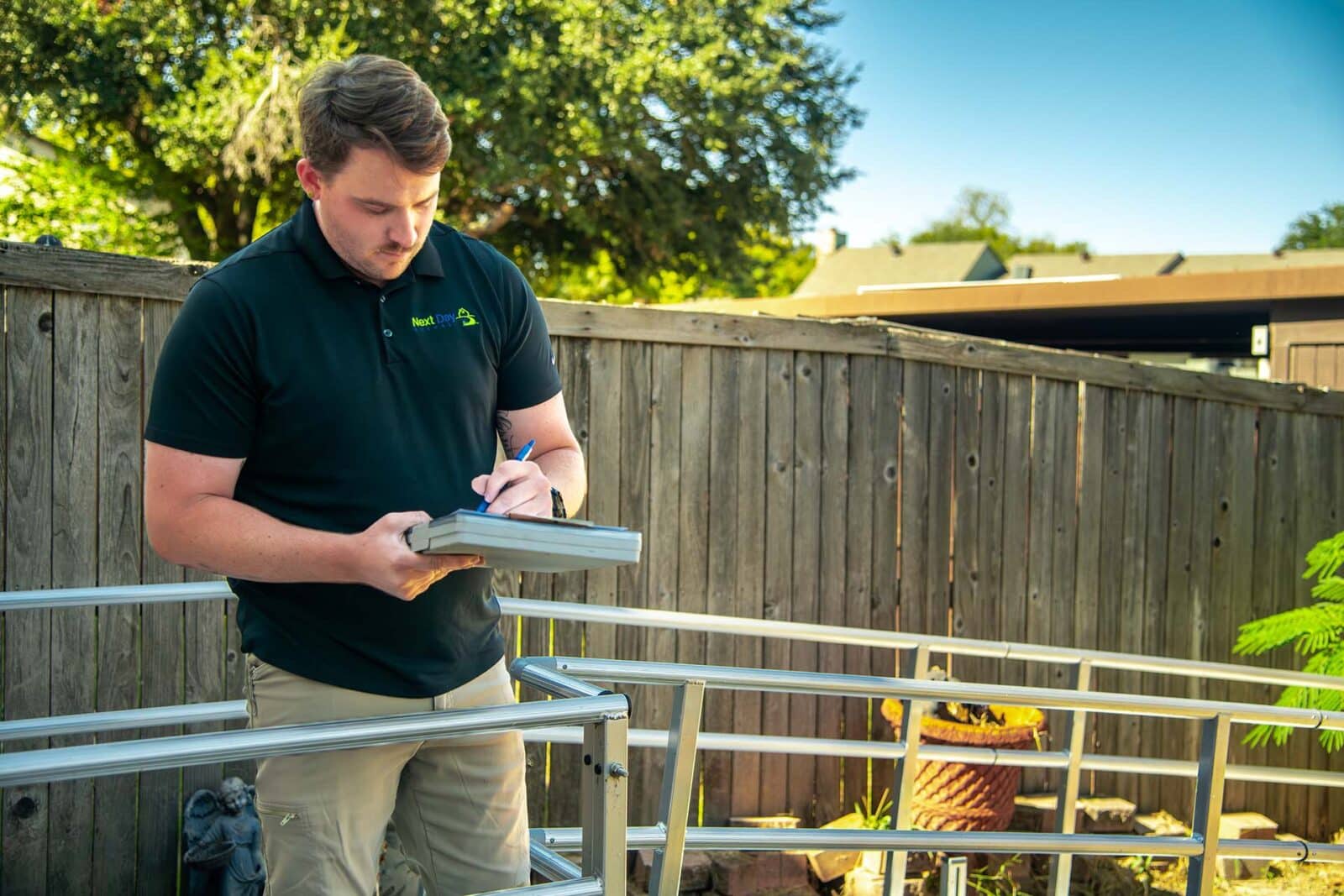 Three men in uniform stand outside next to a pond and discuss build plans