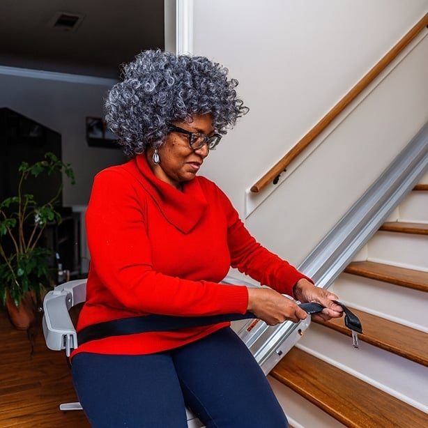 woman in red sweater rides in a stair lift