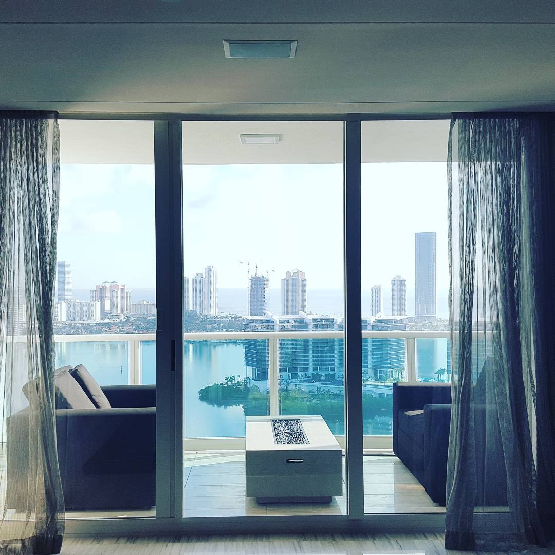 Interior shot looking through a sliding glass door to a downtown balcony with patio furniture
